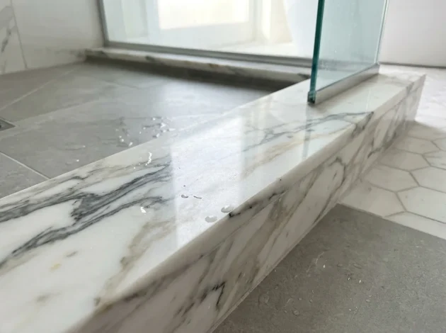 Calacatta Gold Marble threshold used as a shower curb in a walk-in shower