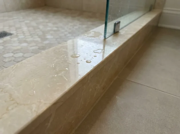 Umbral de mármol Crema Marfil utilizado como bordillo de ducha en una ducha a ras de suelo