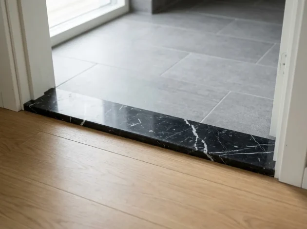 Nero Marquina Marble threshold installed in a doorway between hardwood and tile flooring