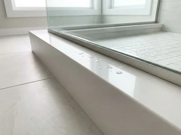 Pure White Quartz threshold used as a shower curb in a walk-in shower