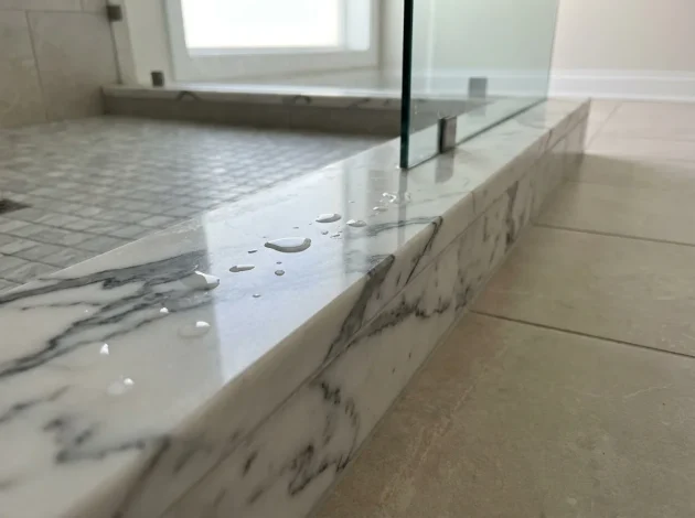 Statuario Marble threshold used as a shower curb in a walk-in shower