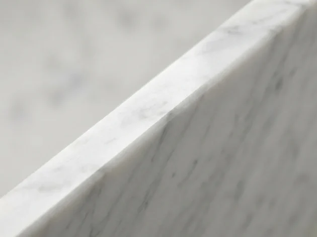 Primer plano del borde biselado pulido de un umbral de mármol blanco de Carrara